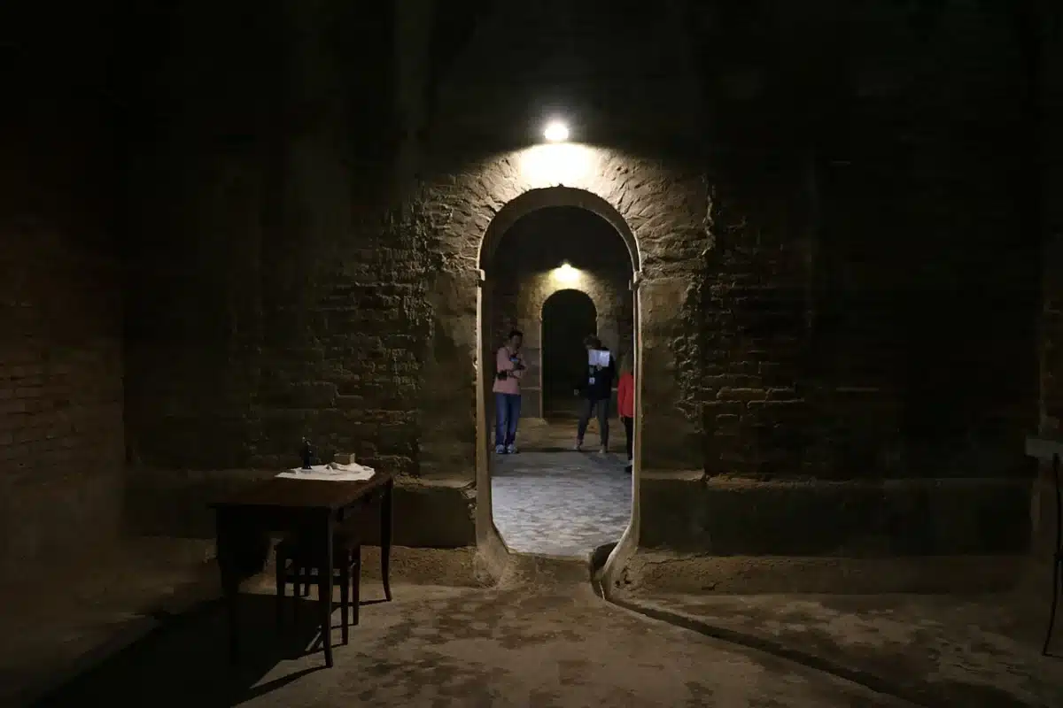 Visitors walking through the lit brick vaulted rooms of the Roman Cisterns under Fermo
