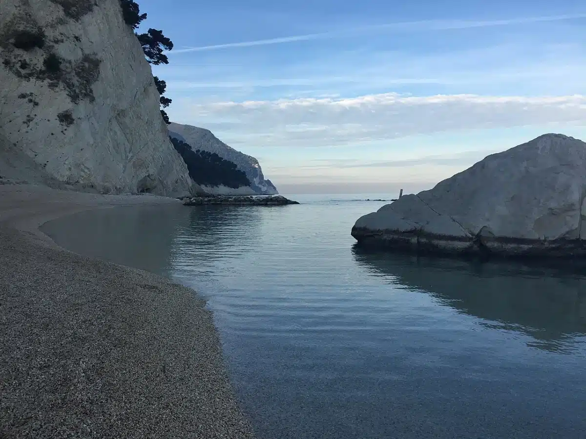 Calm sea and fine gravel beach below the white limestone cliffs of Numana