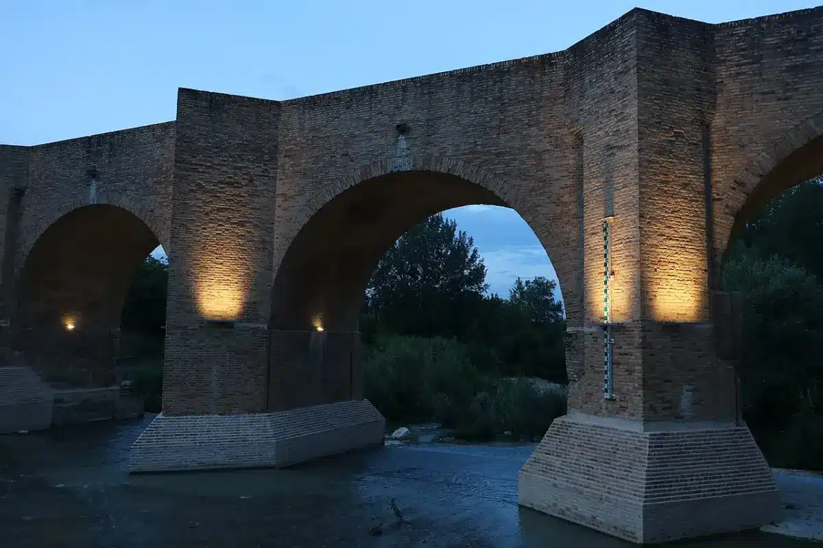 Medieval brick arches of the Ponte del Diavolo bridge in Tolentino lit at dusk